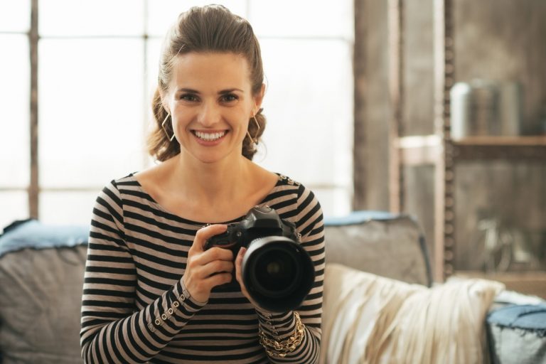 Portrait of happy young woman with modern dslr photo camera Fényképezés otthon - Te mit tudsz összehozni a négy fal között? - NEXTFOTO