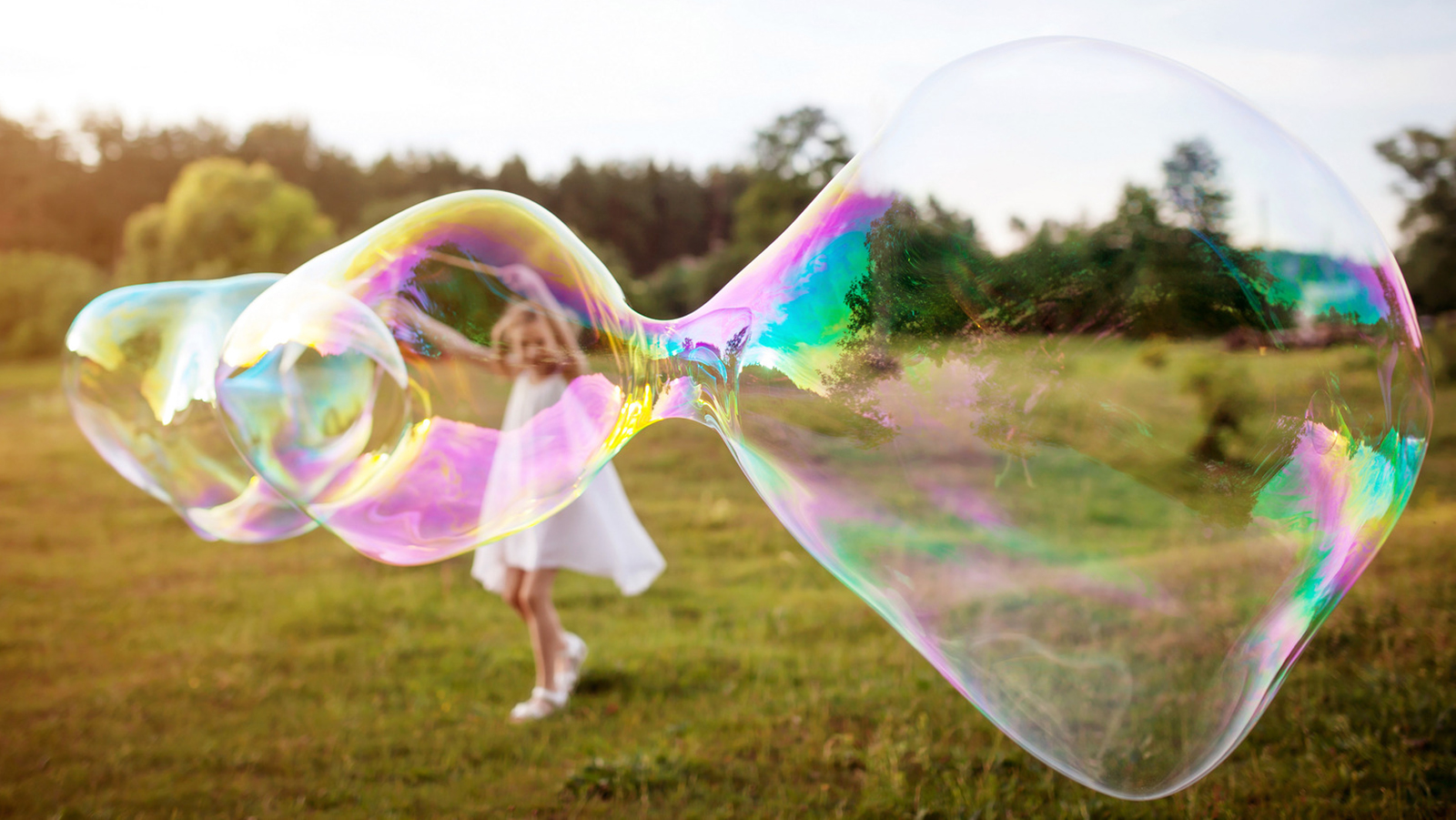 Little girl making a big soap bubble. Focus on the soap bubble. Summer meadow. Örökítsd meg a nyár legizgalmasabb pillanatait! - NEXTFOTO