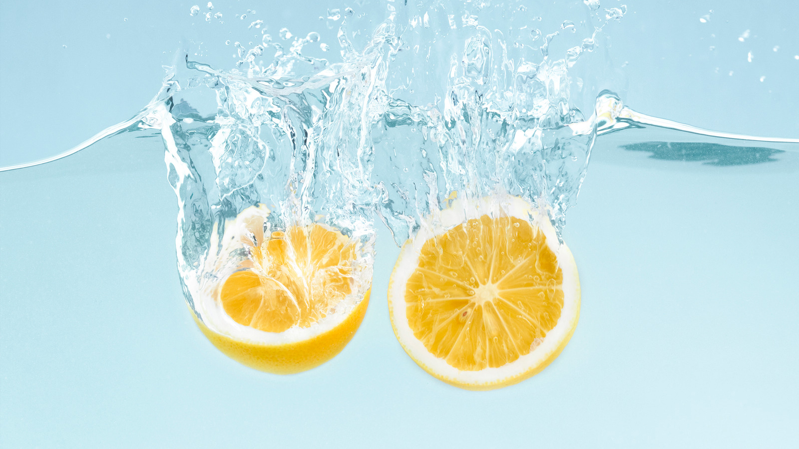 Citrus splash. Lemon halves splattering into clear water on blue background Örökítsd meg a nyár legizgalmasabb pillanatait! - NEXTFOTO